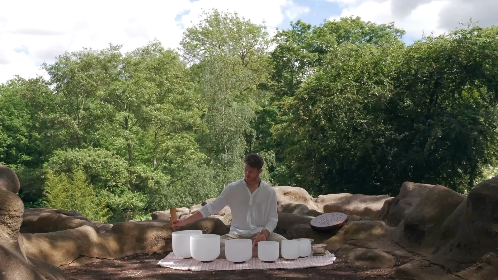 Josh playing crystal singing bowls in a woodland clearing